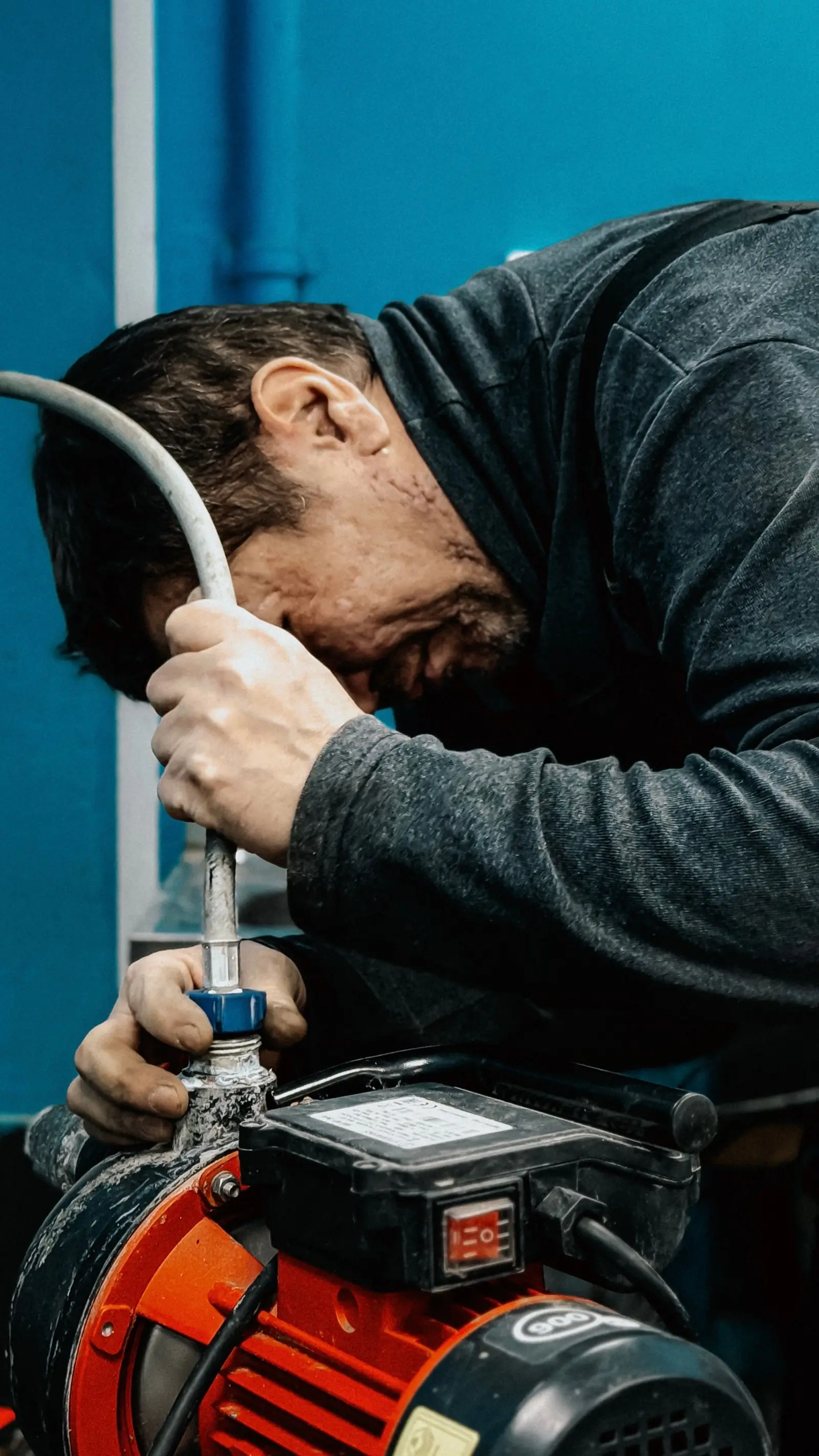 A plumber working on a water pump in a utility room